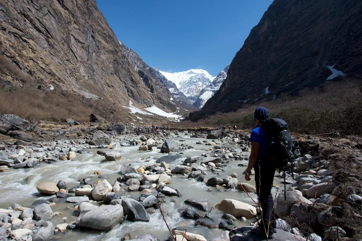 Trekker walking along a high-altitude river valley trail during altitude sickness trekking acclimatisation in Nepal
