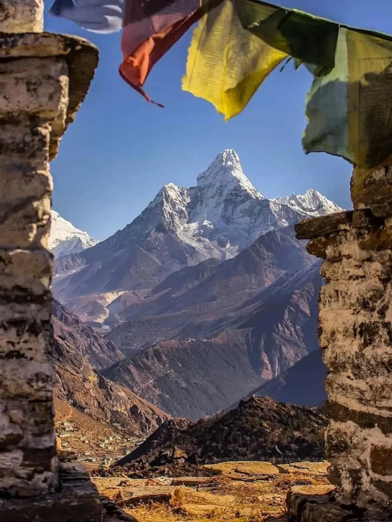 Annapurna base camp trek mountain view framed by stone walls with Himalayan peaks and prayer flags