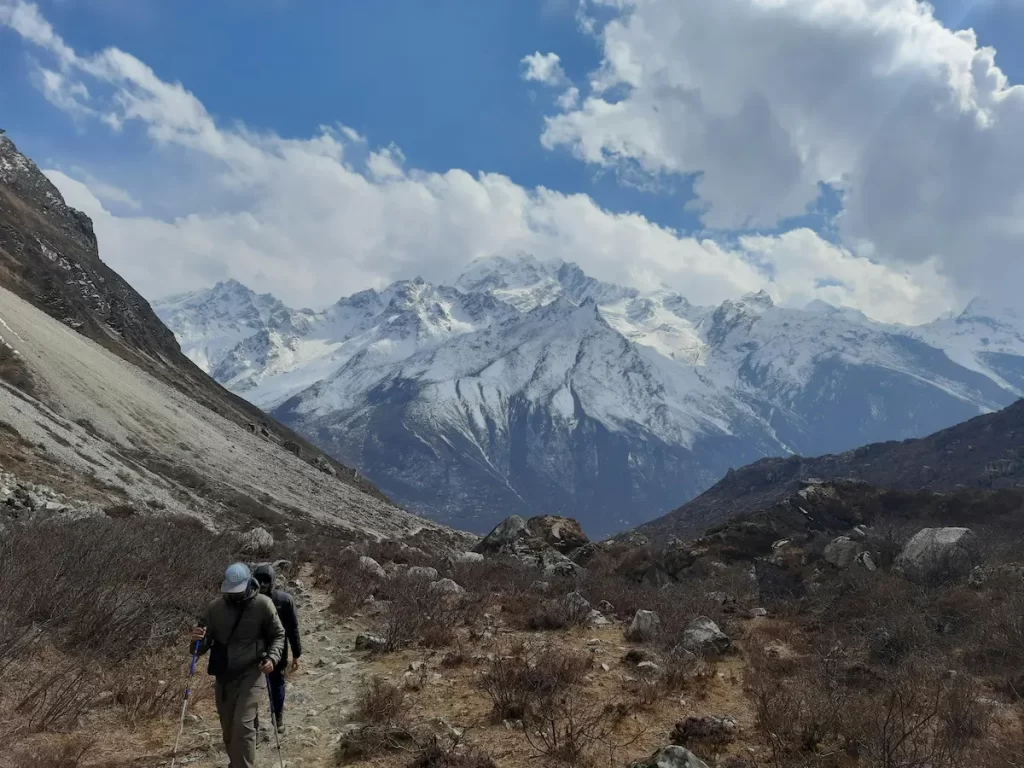 Trekkers walking a mountain trail in Nepal’s Langtang Valley with Himalayan peaks